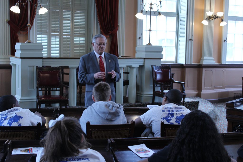 Students sit in the House of Representatives talking to a representative.
