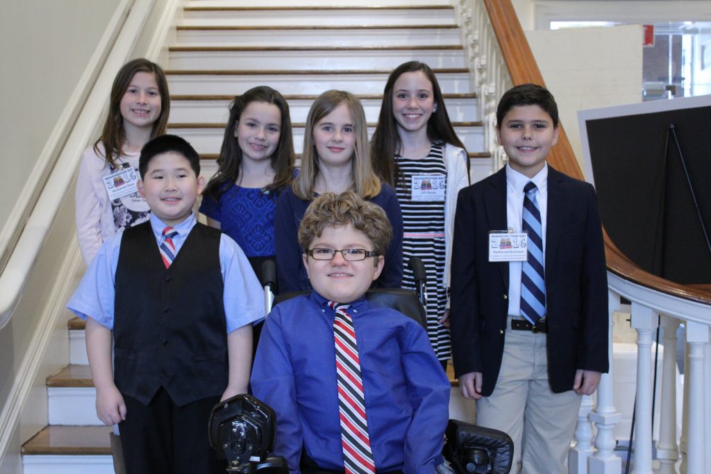 7 students stand on the stairs of the Old State House.,